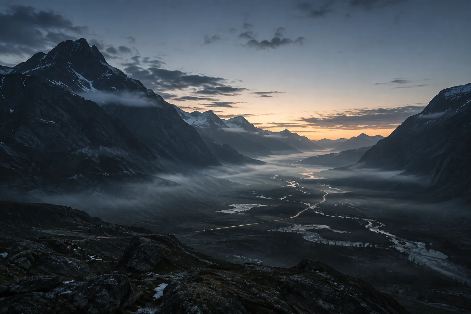 A dark mountain valley opening toward the first light of dawn